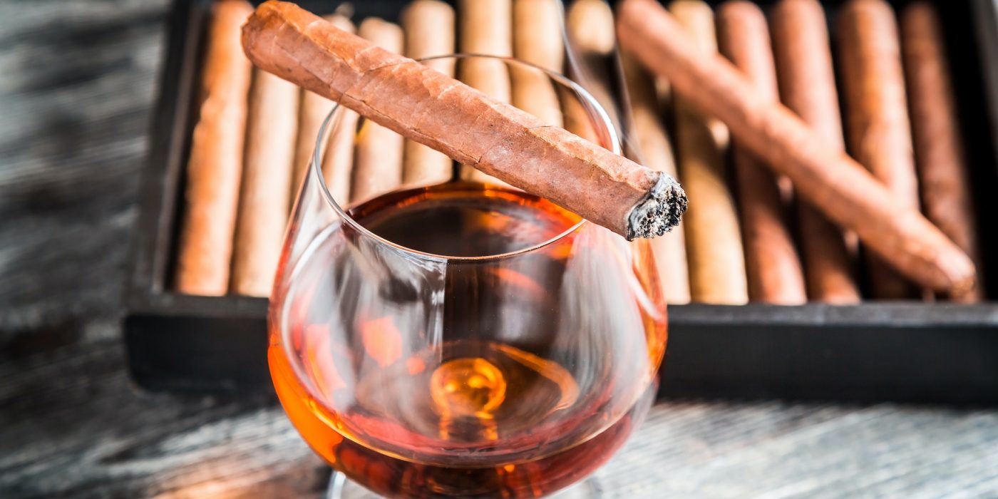 Burning cigar on glass with cognac